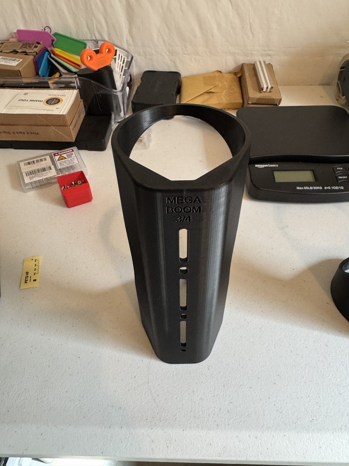 A black 3D-printed MEGABOOM 3/4 speaker mount on the packing bench